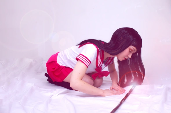 Person in schoolgirl costume kneeling.
